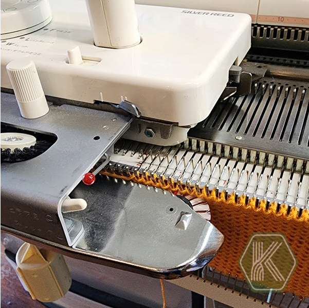 Knitting machine carriage positioned on the left side of the needle bed